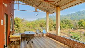 a porch with a table and chairs and a large window at Spring Farm Ville in Alibaug