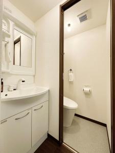 a white bathroom with a sink and a toilet at bHOTEL Nagomi - Comfy 1 Bedroom in City Center for 3ppl in Hiroshima