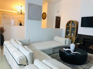 a living room with white couches and a tv at Bluebanana Lodge in Mthatha