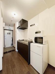 廣島的住宿－bHOTEL Nagomi - Comfy 1 Bedroom in City Center for 3ppl，厨房配有微波炉和炉灶。