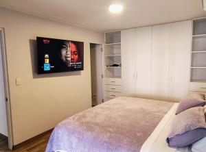 a bedroom with a bed and a tv on the wall at Apartamento en Miraflores con AC in Lima
