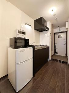 uma cozinha com um micro-ondas e um frigorífico em bHOTEL Nagomi - Stylish 1 BR Apt near City Centre for 3Ppl em Hiroshima