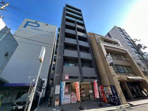 廣島的住宿－bHOTEL Nagomi - Stylish 1 BR Apt near City Centre for 3Ppl，前面有停车计数器的高楼