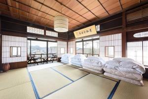 Habitación con varias camas blancas en una habitación con ventanas. en bLOCAL Bingo Yamamo - Experience at Traditional Japanese House, en Onomichi