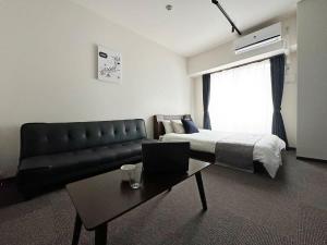 a bedroom with a bed and a couch and a table at bHOTEL Nagomi - 1 Bedroom Apt in City Centre w balcony for 3 Ppl in Hiroshima