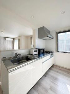 a kitchen with white cabinets and a sink at bHOTEL Yutori - Spacious 2BR Apartment very near the Station in Onomichi