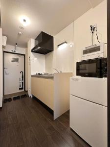 uma cozinha com armários brancos e um forno com placa de fogão em bHOTEL Nagomi - 1 Bedroom Apt in City Centre w balcony for 3 Ppl em Hiroshima