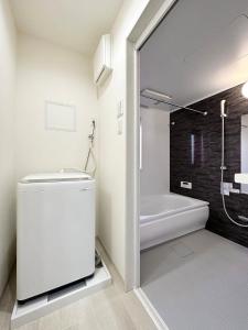 a bathroom with a shower and a toilet and a tub at bHOTEL Yutori - Spacious 2BR Apartment very near the Station in Onomichi