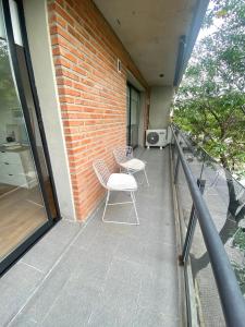 balkon z 2 krzesłami i ceglaną ścianą w obiekcie Depto Genova, Zona Norte, Cochera disponible w mieście Rosario