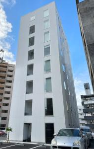 a car parked in front of a white building at bHOTEL Arts Dobashi - Studio Apt for 6 Ppl Near Peace Park in Hiroshima