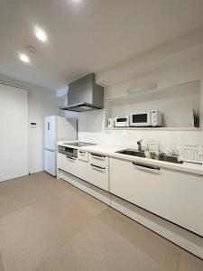una cucina bianca con lavandino e frigorifero di bLOCAL Itsuki - Charming Private House in Miyajimaguchi Near Itsukushima Shrine Upto 18 ppl a Hatsukaichi