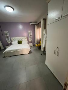 - une chambre avec un lit blanc et un mur violet dans l'établissement COMPLEXE BLUE PHOENIX, à Dakar