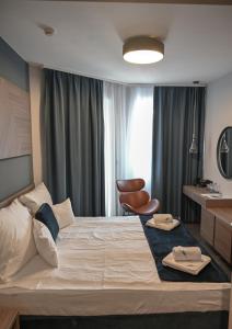 una habitación de hotel con una cama grande y una silla en NN Boutique Hotel****, en Tiszaújváros