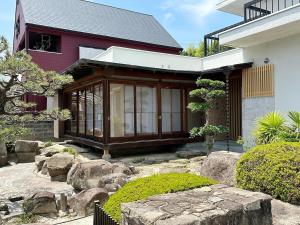 a red house with a garden and rocks in front of it at bLOCAL Itsuki - Charming Private House in Miyajimaguchi Near Itsukushima Shrine Upto 18 ppl in Hatsukaichi