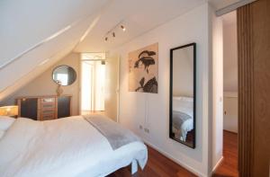 1 dormitorio con cama blanca y espejo grande en De Mors Bungalow nabij zwembad en golfbaan, en Delden