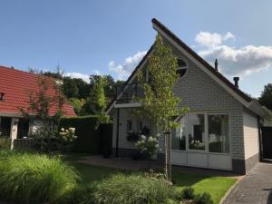 una casa con un árbol en el patio delantero en De Mors Bungalow nabij zwembad en golfbaan, en Delden