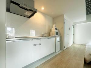 a white kitchen with a sink and a microwave at bHOTEL Arts Dobashi - New Studio Apt in the City Center for 6Ppl in Hiroshima +25 photos