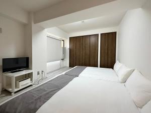 a bedroom with a large white bed and a flat screen tv at Mitao bld - Beautiful Apt for 10Ppl Very Near to Peace Park in Kami-nagarekawachō