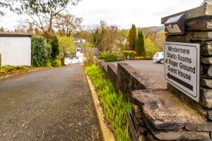 a sign on a stone wall next to a street at Windermere Studio Rooms in Windermere