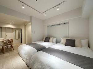 two beds in a large room with a table at bHOTEL F-style - Cozy New Apt in the Heart of the City in Hiroshima