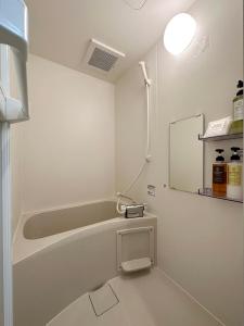 a bathroom with a bath tub and a mirror at bHOTEL F-style - Cozy New Apt in the Heart of the City in Hiroshima