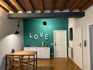 une salle à manger avec un mur vert avec le mot amour dans l'établissement Maison Vert appartamento in centro storico a Modena, à Modène
