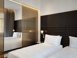 una camera d'albergo con due letti e uno specchio di art'otel Rome Piazza Sallustio, Powered by Radisson Hotels a Roma