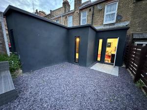 a house with a black wall and a driveway at 2 bedroom flat Wembley in London
