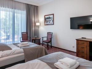 ein Hotelzimmer mit zwei Betten und einem Fernseher in der Unterkunft Medica Hotel Krojanty Bory Tucholskie in Chojnice