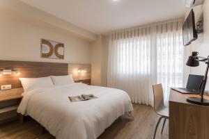 Cette chambre comprend un lit et un bureau avec un ordinateur portable. dans l'établissement Vigo Bay Apartments by Olala Homes, à Vigo