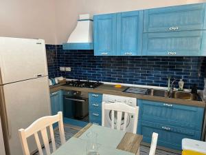 a kitchen with blue cabinets and a table and a refrigerator at MareaSol Casa Vacanze in Santa Maria di Castellabate