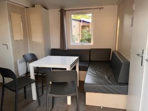 un piccolo soggiorno con tavolo e sedie di Mobil home Clim, Tv - Camping Falaise Narbonne Plage 4 étoiles - 004 a Narbonne-Plage