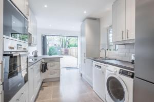 een keuken met witte kasten en een wasmachine en droger bij Refurbished High Spec CENTRAL Family Home in Cambridge