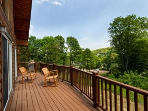 a deck with two chairs and a grill on it at Berkshire Vacation Rentals: Great Barrington Cabin Sleeps 14 Walk To Town in Great Barrington