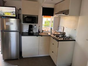 La cuisine est équipée d'un réfrigérateur en acier inoxydable et d'un évier. dans l'établissement Mobil home Clim, Tv - Camping Falaise Narbonne Plage 4 étoiles - 004, à Narbonne-Plage