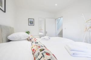 a white bedroom with two beds with white pillows at Refurbished High Spec CENTRAL Family Home in Cambridge