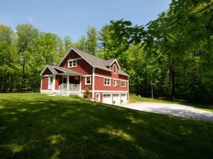 a red house on a grassy hill with trees at Berkshire Vacation Rentals: Peaceful Post and Beam Loft Sleeps 9 in New Marlborough