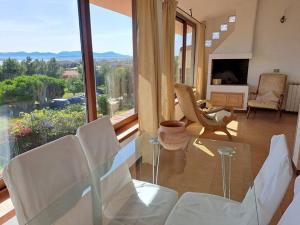 uma sala de estar com cadeiras brancas e uma grande janela em Nice Apartment in Margine Rosso em Quartu SantʼElena
