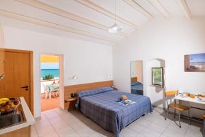 um quarto com uma cama, uma cozinha e uma mesa em Crovatico Club Vacanze em Vieste