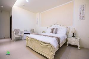 馬公市的住宿－澎湖森源民宿 SunYoung，卧室配有一张白色大床和一把椅子