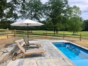 a chair and an umbrella next to a swimming pool at Berkshire Vacation Rentals: Private Estate Heated YEARROUND Outdoor Pool in North Egremont
