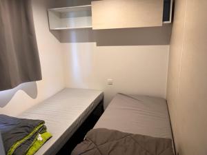una piccola camera con due letti e un armadio di Mobil home Clim, Tv - Camping Falaise Narbonne Plage 4 étoiles - 004 a Narbonne-Plage