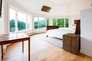 1 dormitorio con 1 cama, escritorio y ventanas en Berkshire Vacation Rentals: The Brookman: Renovated 6000 SF Estate On 40 Acres, en Williamstown