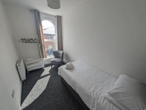 a bedroom with a bed and a chair and a window at Seaview House - Flat 2 in Lowestoft