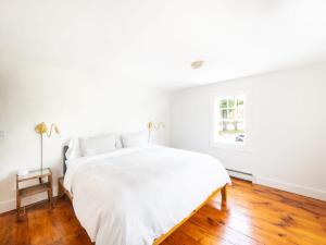 a white bedroom with a bed and a window at Berkshire Vacation Rentals: Stunning 1860 Farmhouse Private Pond & Hot Tub in Taghkanic