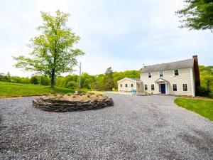 a large driveway with a stone circle in front of a white house at Berkshire Vacation Rentals: Stunning 1860 Farmhouse Private Pond & Hot Tub in Taghkanic