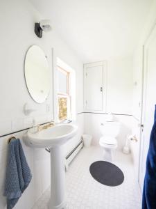 a white bathroom with a sink and a toilet at Berkshire Vacation Rentals: Stunning 1860 Farmhouse Private Pond & Hot Tub in Taghkanic