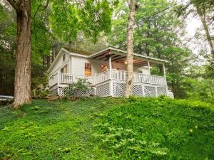 Berkshire Vacation Rentals: Private Cottage Come Enjoy Nature في Canaan: بيت أبيض على تلة فيها أشجار وعشب