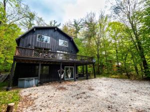 una cabaña negra en el bosque con una entrada de grava en Berkshire Vacation Rentals: Beautiful Barn Style Home On Otis Reservoir, en East Otis