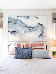 a white bed with pillows and a painting above it at Tranquil Views On Planting Island Cove in Marion